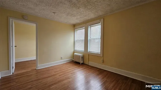 an empty room with wooden floor and window
