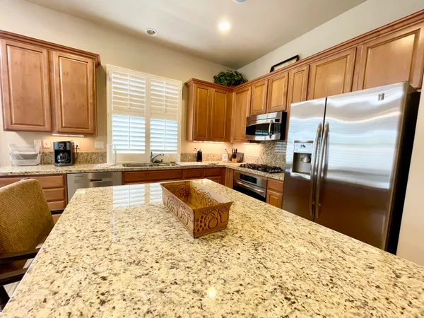 a kitchen with granite countertop a refrigerator sink stove microwave and cabinets