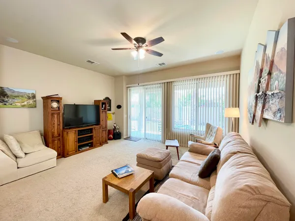 a living room with furniture ceiling fan and a flat screen tv