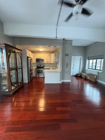 a view of a livingroom with furniture wooden floor and a kitchen