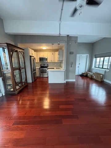 a view of an empty room with window and wooden floor
