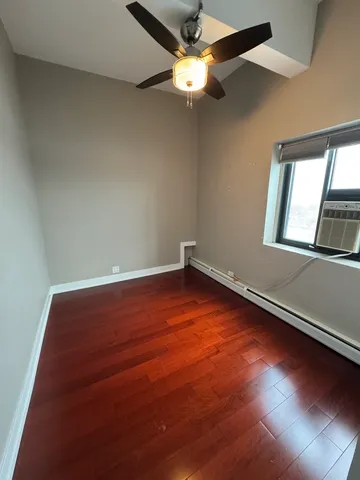 an empty room with wooden floor fan and windows