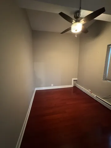 an empty room with wooden floor and fan