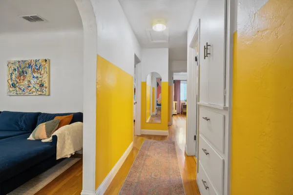 a view of a hallway with wooden floor and furniture