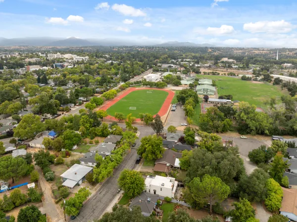 an aerial view of residential houses with outdoor space and trees