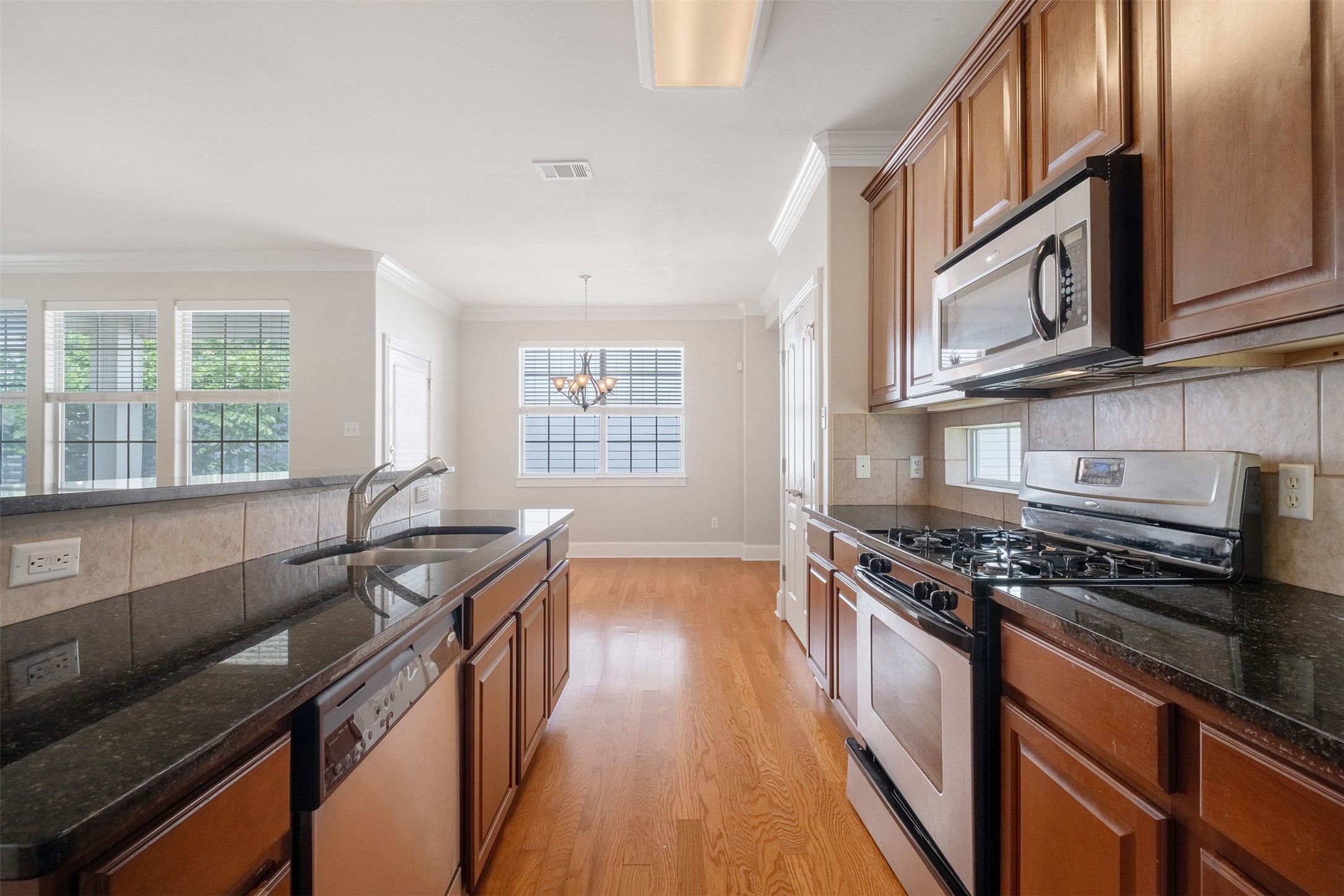 6715 Windrift Way, Unit 8 Austin, TX 78745 - Photo 8 of 24 A well-appointed kitchen features rich wood cabinetry, lustrous granite countertops, and seamless hardwood flooring.