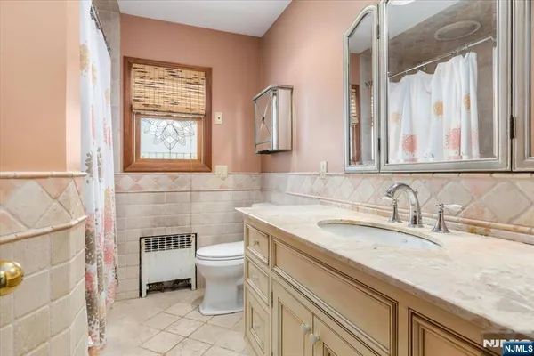 a bathroom with a toilet a sink a mirror a window and vanity