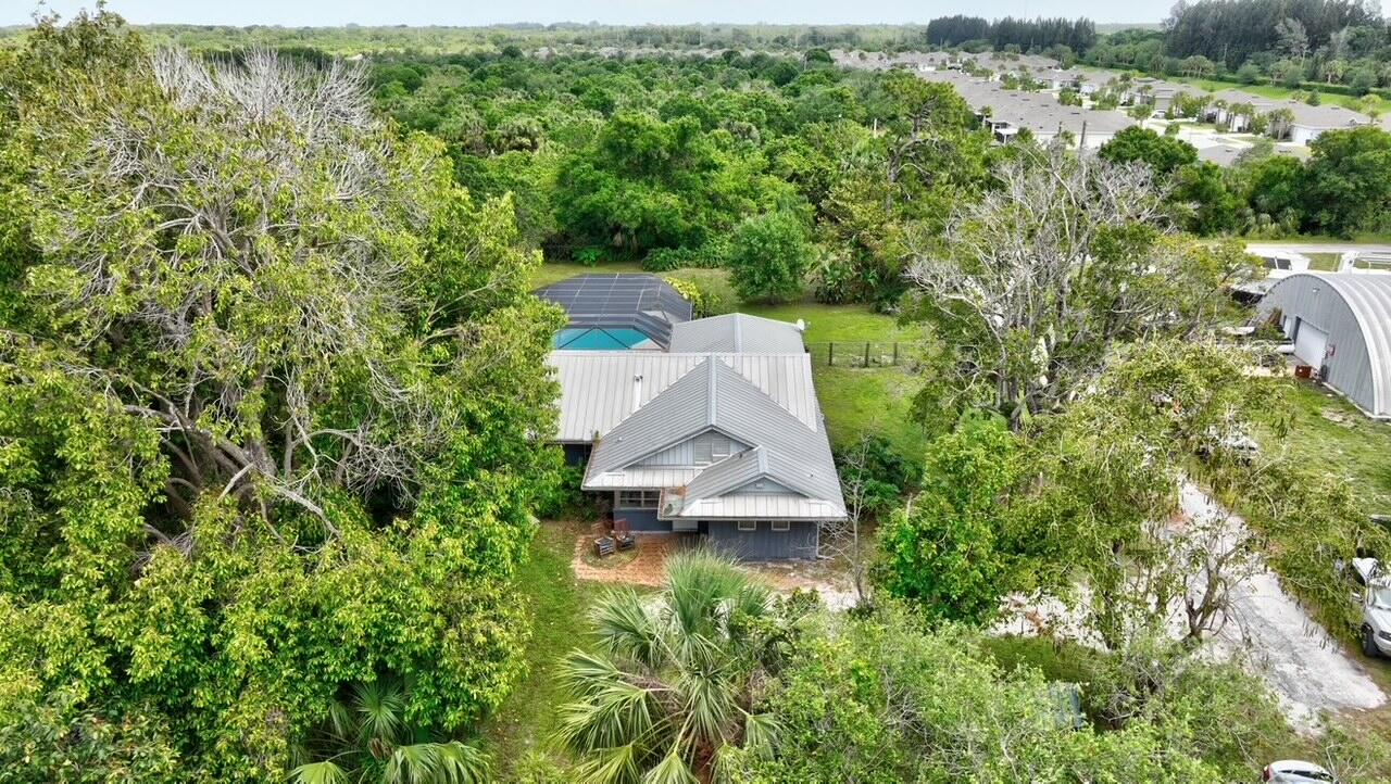 an aerial view of residential house with outdoor space and trees all around