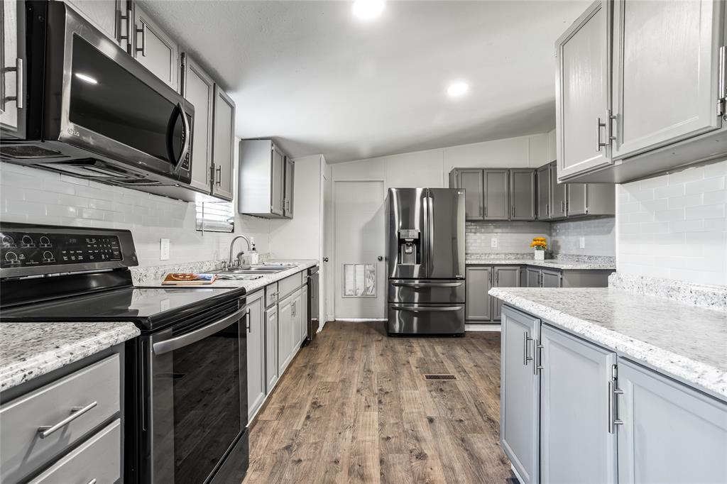 112 Pine Ridge Circle Southmayd, TX 75092 - Photo 8 of 25 a kitchen with stainless steel appliances granite countertop a stove top oven a sink dishwasher a refrigerator and cabinets with wooden floor