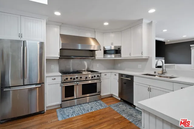 a kitchen with stainless steel appliances kitchen island granite countertop a stove a sink and a refrigerator