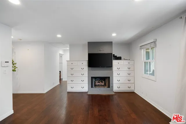 an empty room with furniture a flat screen tv and a fireplace