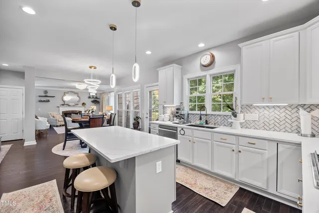 a open kitchen with stainless steel appliances granite countertop a stove top oven a refrigerator and white cabinets with wooden floor