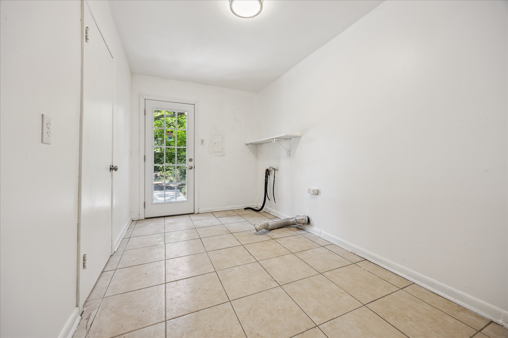 5419 Beechnut Street Houston, TX 77096 - Photo 22 of 28 Spacious utility room with tile flooring, storage closet and exterior access through a glass door to the backyard.