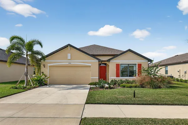 a front view of a house with a yard and potted plants