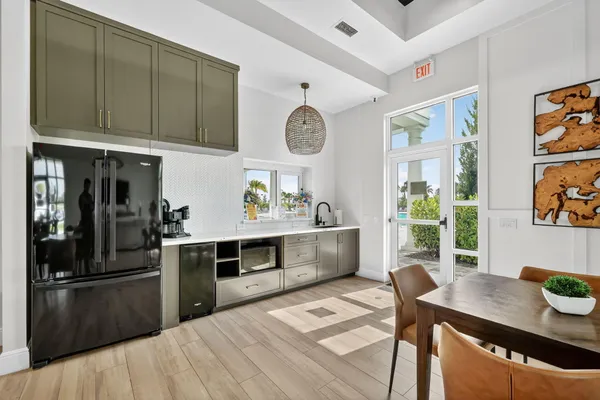 a kitchen with stainless steel appliances granite countertop a refrigerator a sink dishwasher a stove and a dining table with wooden floor