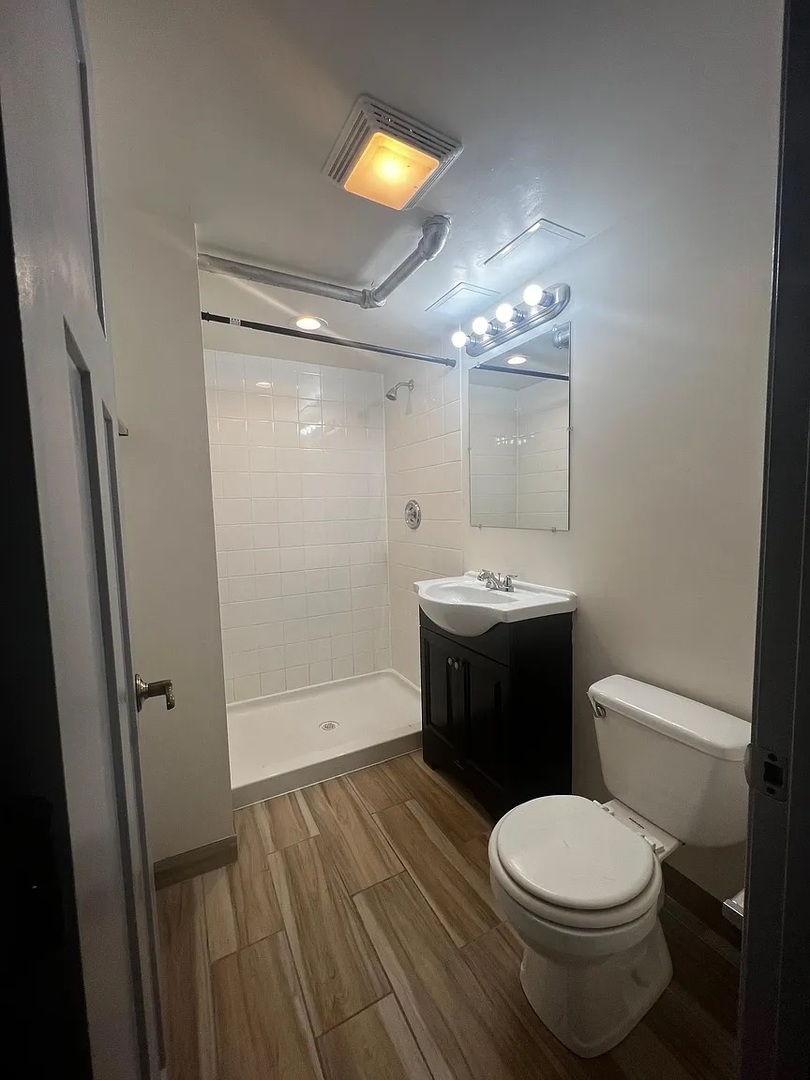 4304 West Shakespeare Avenue Chicago, IL 60639 - Photo 6 of 6 a bathroom with a toilet a sink and mirror