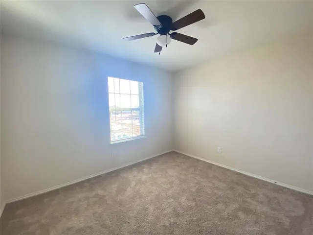 an empty room with a window and a fan