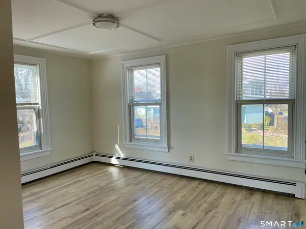 a view of an empty room with wooden floor and a window