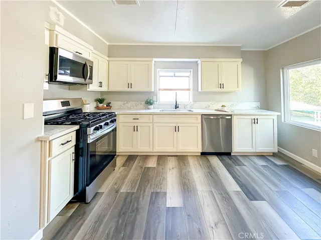 a kitchen with granite countertop wooden floor stainless steel appliances and sink