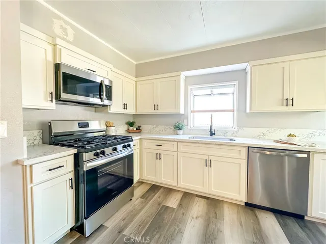 a kitchen with granite countertop a sink cabinets stainless steel appliances and a window