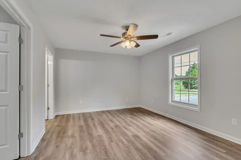 an empty room with wooden floor and windows
