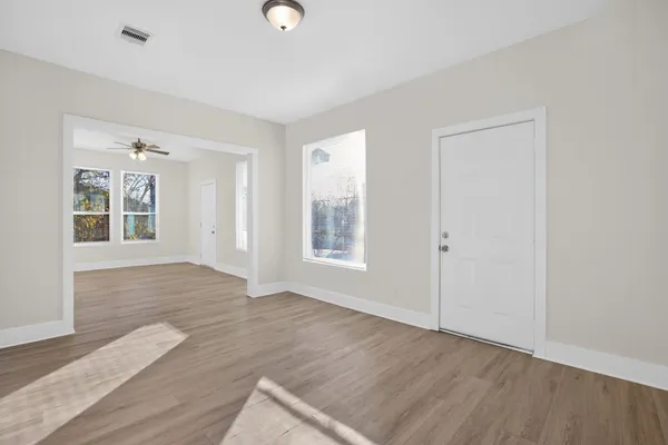 an empty room with wooden floor and windows