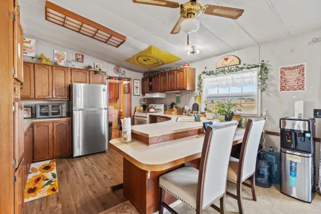 a kitchen with stainless steel appliances granite countertop a table chairs and a refrigerator