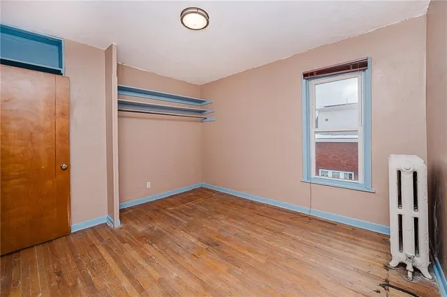 a view of an empty room with window and wooden floor