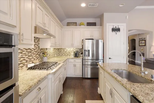 a kitchen with stainless steel appliances granite countertop a sink stove and refrigerator
