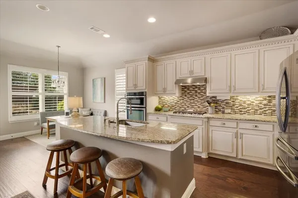 a kitchen with stainless steel appliances granite countertop a stove a sink a microwave a dining table and chairs