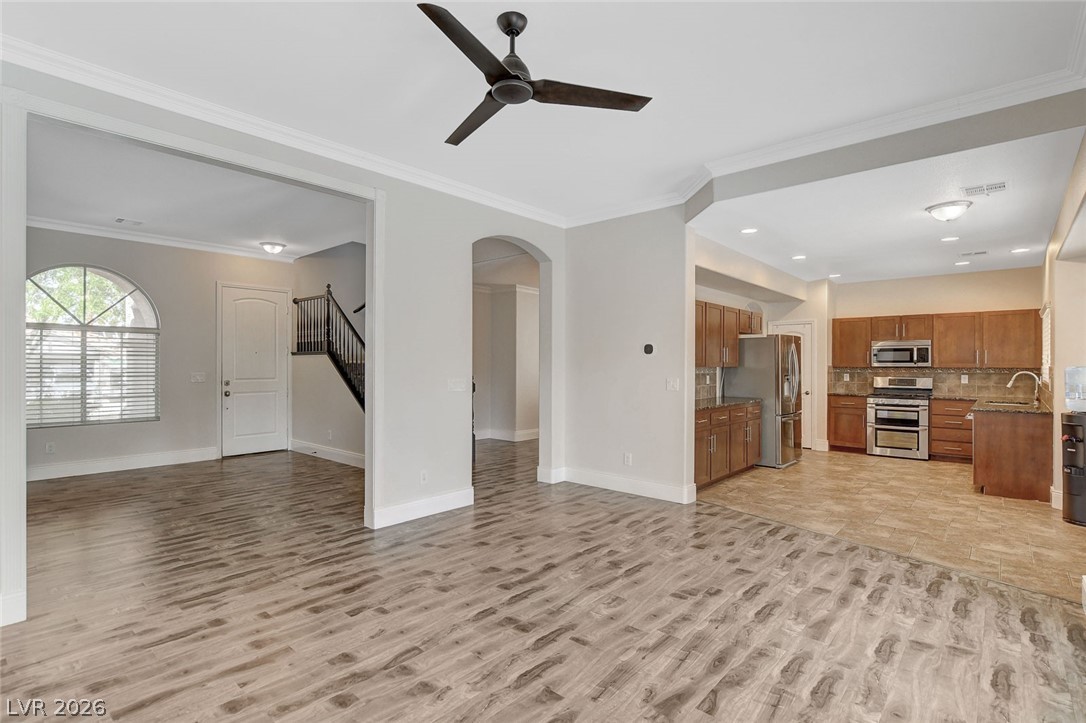 191 Verde Ridge Court Henderson, NV 89012 - Photo 9 of 36 Unfurnished living room with a sink, light wood finished floors, arched walkways, a ceiling fan, and stairway
