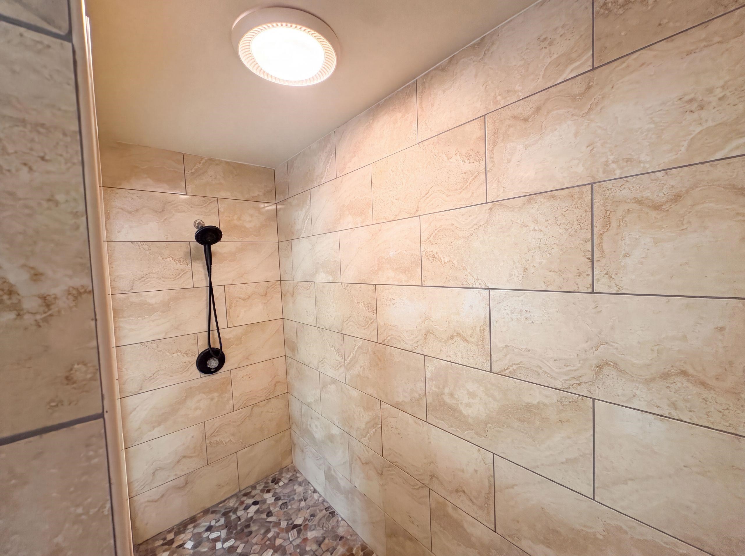 9424 Gotten Road Germantown, TN 38139 - Photo 24 of 27 Walk-in shower with large-format rectangular tile walls, a pebble-stone floor, and a matte black shower fixture