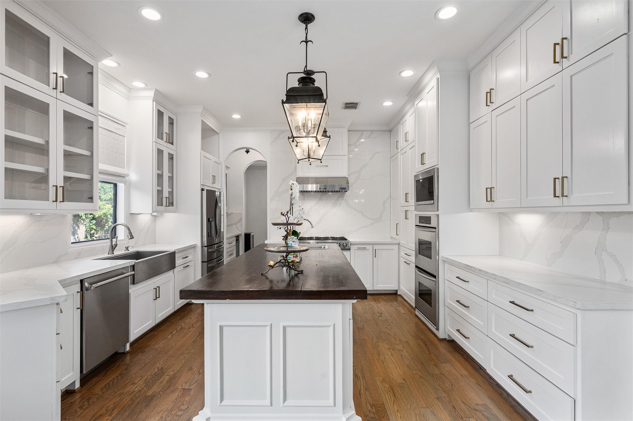 4523 Maple Street Bellaire, TX 77401 - Photo 11 of 50 Welcome to the heart of the home—the fully remodeled kitchen. Timeless updates include marbled quartz countertops, white shaker-style cabinetry extending to the ceiling, stainless steel appliances, and a large island with a contrasting countertop for both style and function.