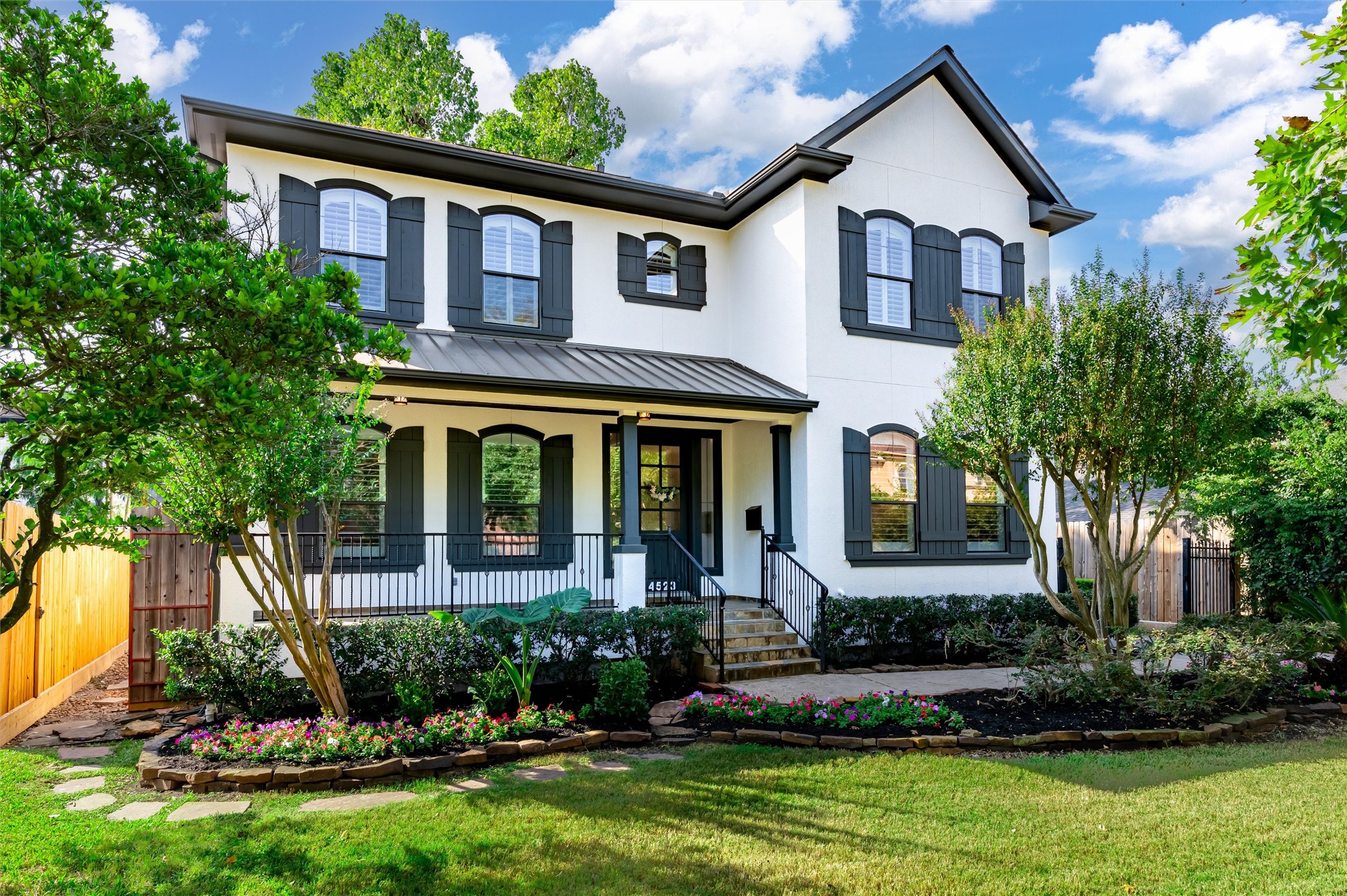 4523 Maple Street Bellaire, TX 77401 - Photo 2 of 50 The exterior showcases timeless design with freshly painted stucco accented by striking black shutters. Expansive windows and a spacious front porch with elegant wrought iron railing create a stunning first impression. The roof was replaced in October 2025!
