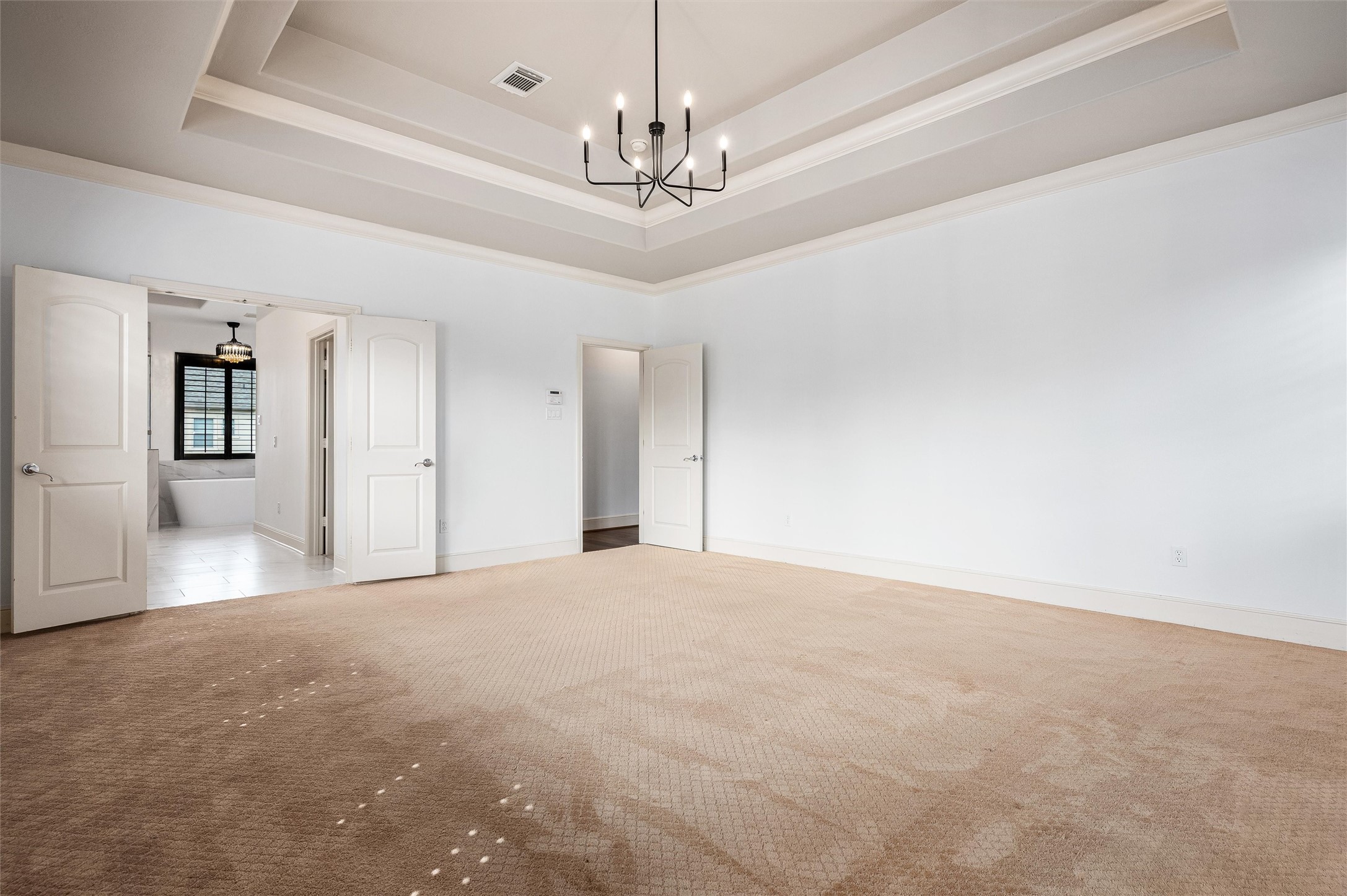 4523 Maple Street Bellaire, TX 77401 - Photo 25 of 50 The double tray ceiling, highlighted by an elegant lighting fixture, adds a striking focal point. The suite offers ample space for a large king-size bed and additional furnishings.