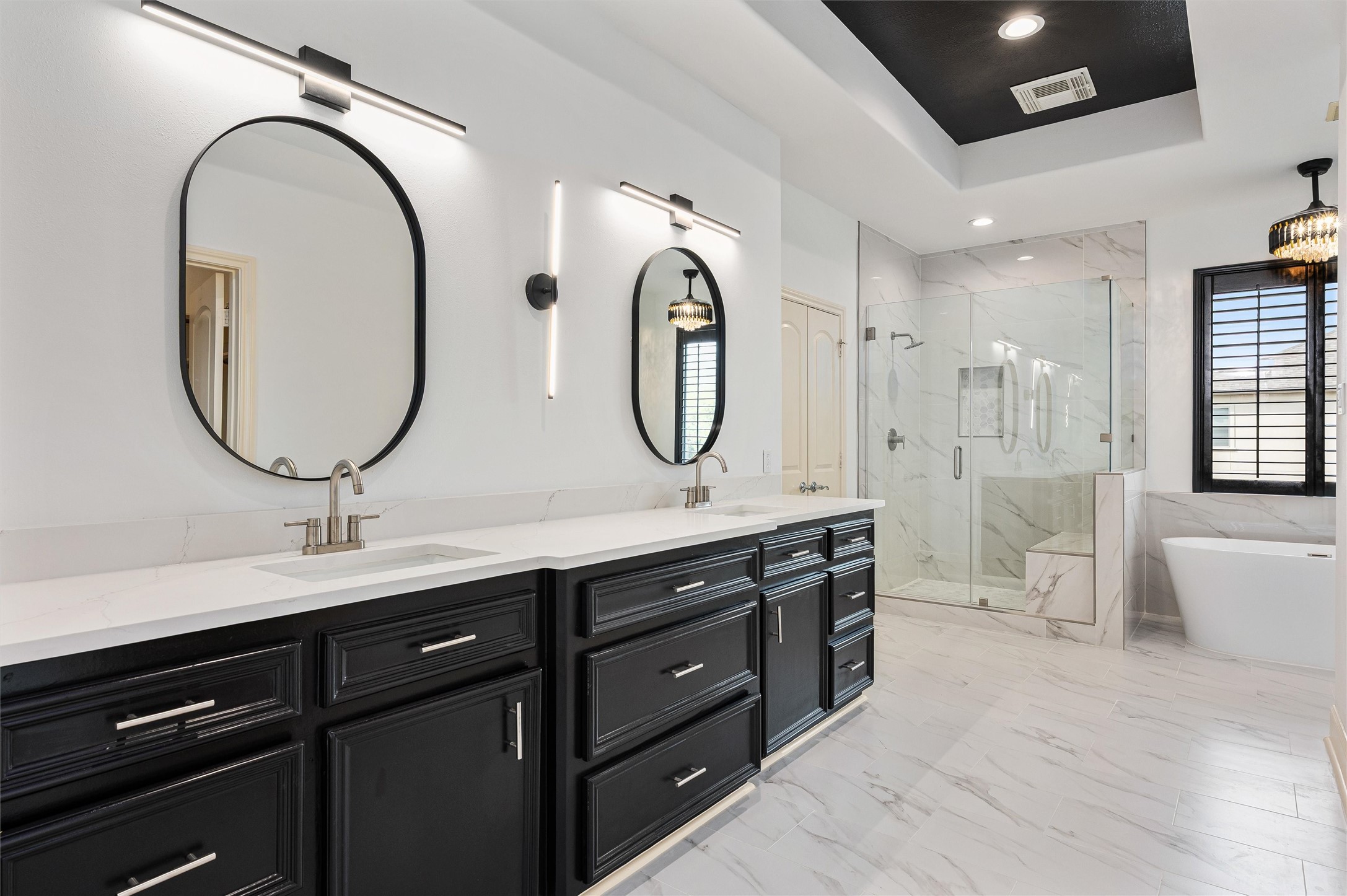 4523 Maple Street Bellaire, TX 77401 - Photo 26 of 50 Step into the fully renovated primary ensuite, designed with a spa-like feel. Features include a spacious dual-sink vanity with quartz countertops, updated faucets, and two framed mirrors beneath modern lighting fixtures.