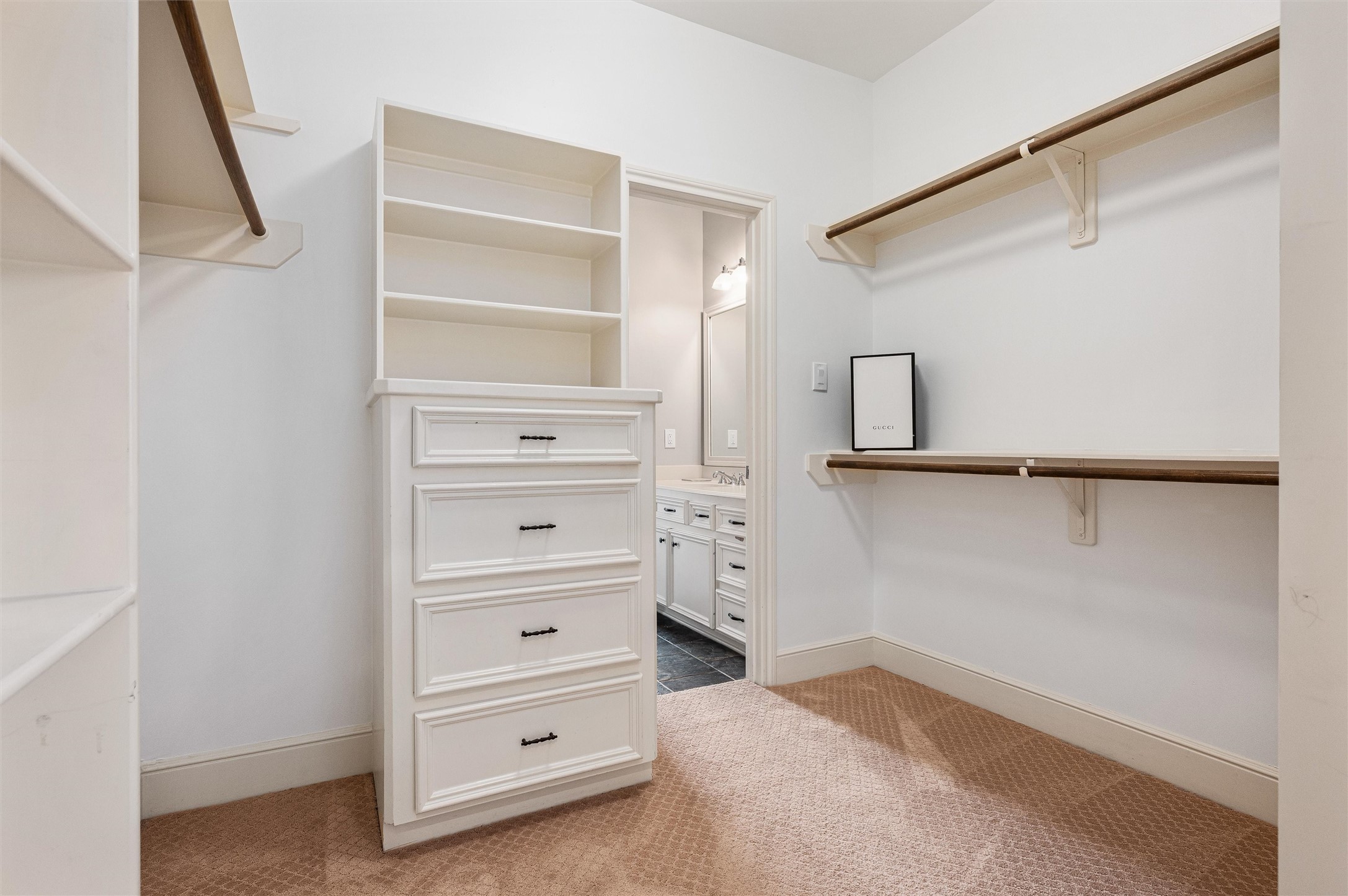 4523 Maple Street Bellaire, TX 77401 - Photo 30 of 50 Welcome to the primary walk-in closet, featuring plush carpet, custom built-ins with drawers and shelves, and perimeter shelving and hanging racks designed to accommodate a large wardrobe.
