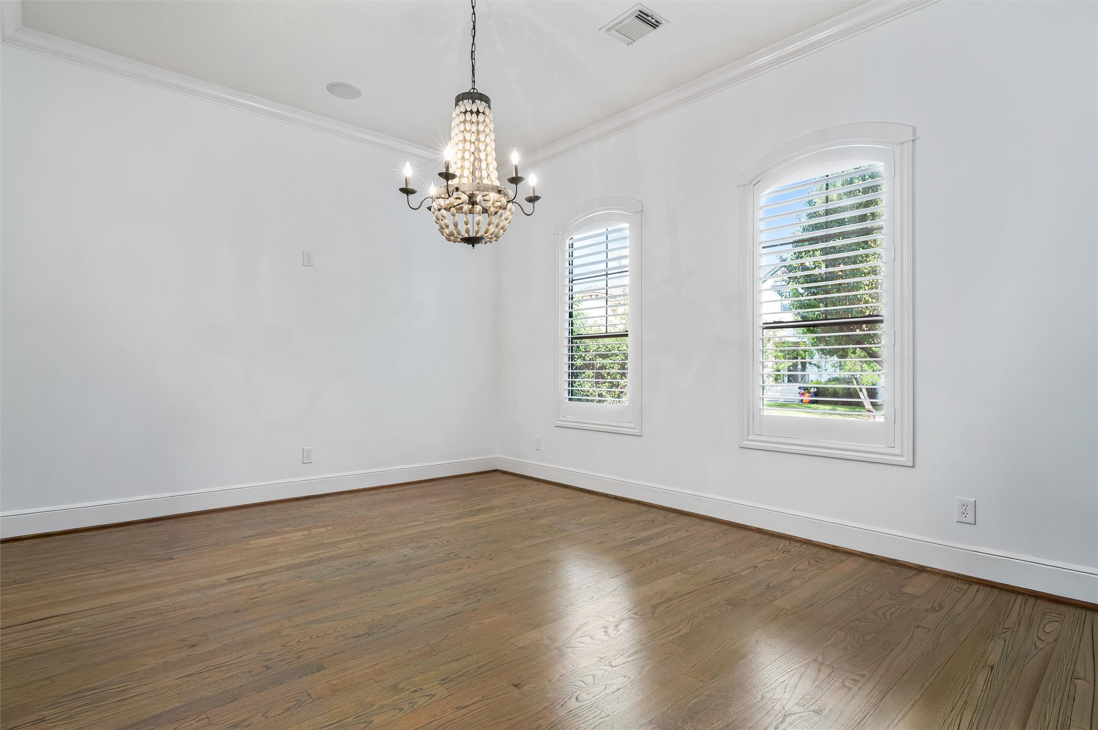 4523 Maple Street Bellaire, TX 77401 - Photo 8 of 50 The formal dining room, located just off the foyer, features hardwood floors, fresh paint, and two arched windows overlooking the front yard. A beautiful chandelier serves as the focal point, adding an elegant touch to the space.