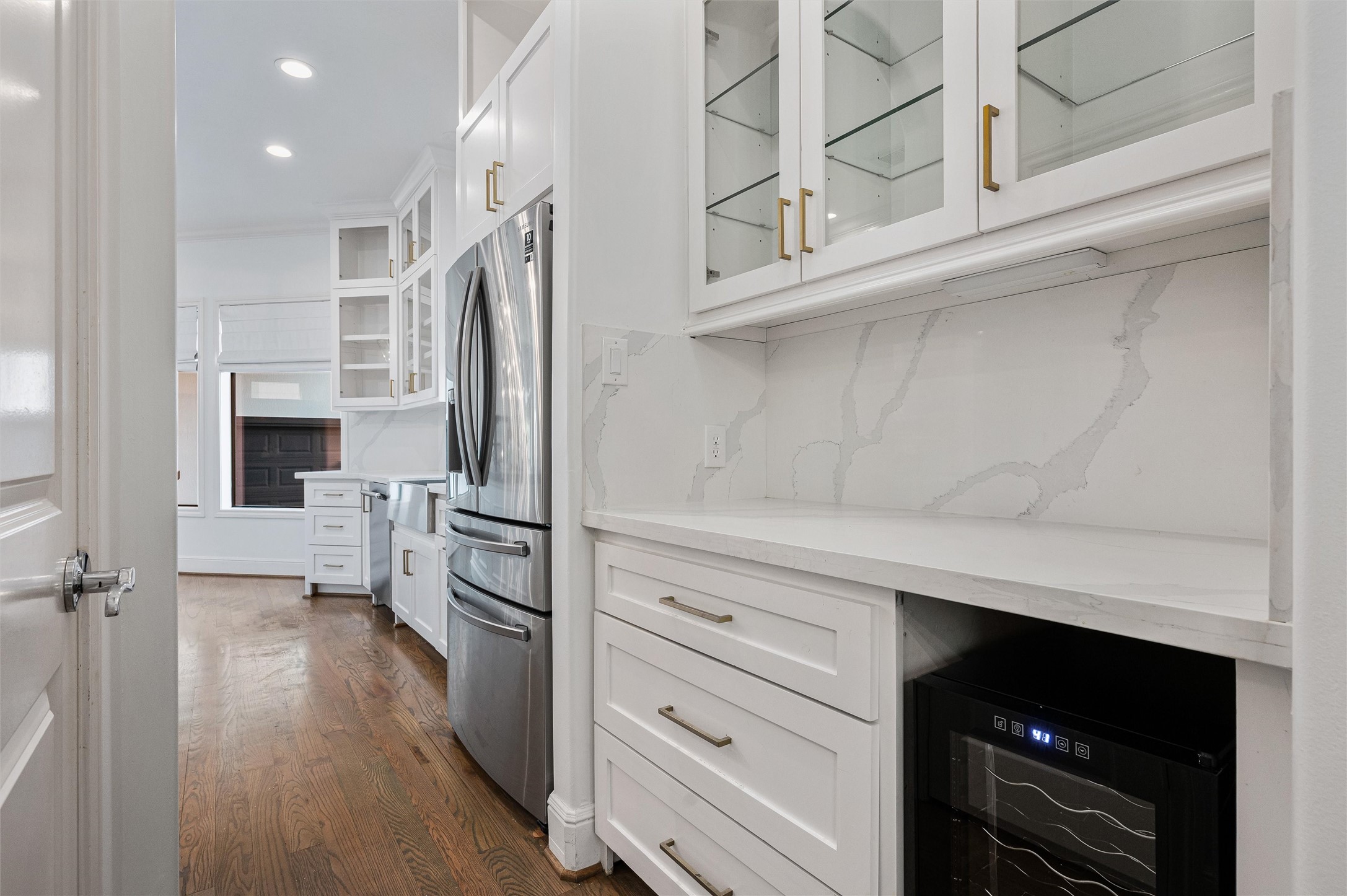 4523 Maple Street Bellaire, TX 77401 - Photo 10 of 50 The butler’s pantry features shaker-style drawers with updated hardware, a wine fridge, and upper cabinets with glass fronts and quartz countertops, leading seamlessly into the remodeled kitchen.
