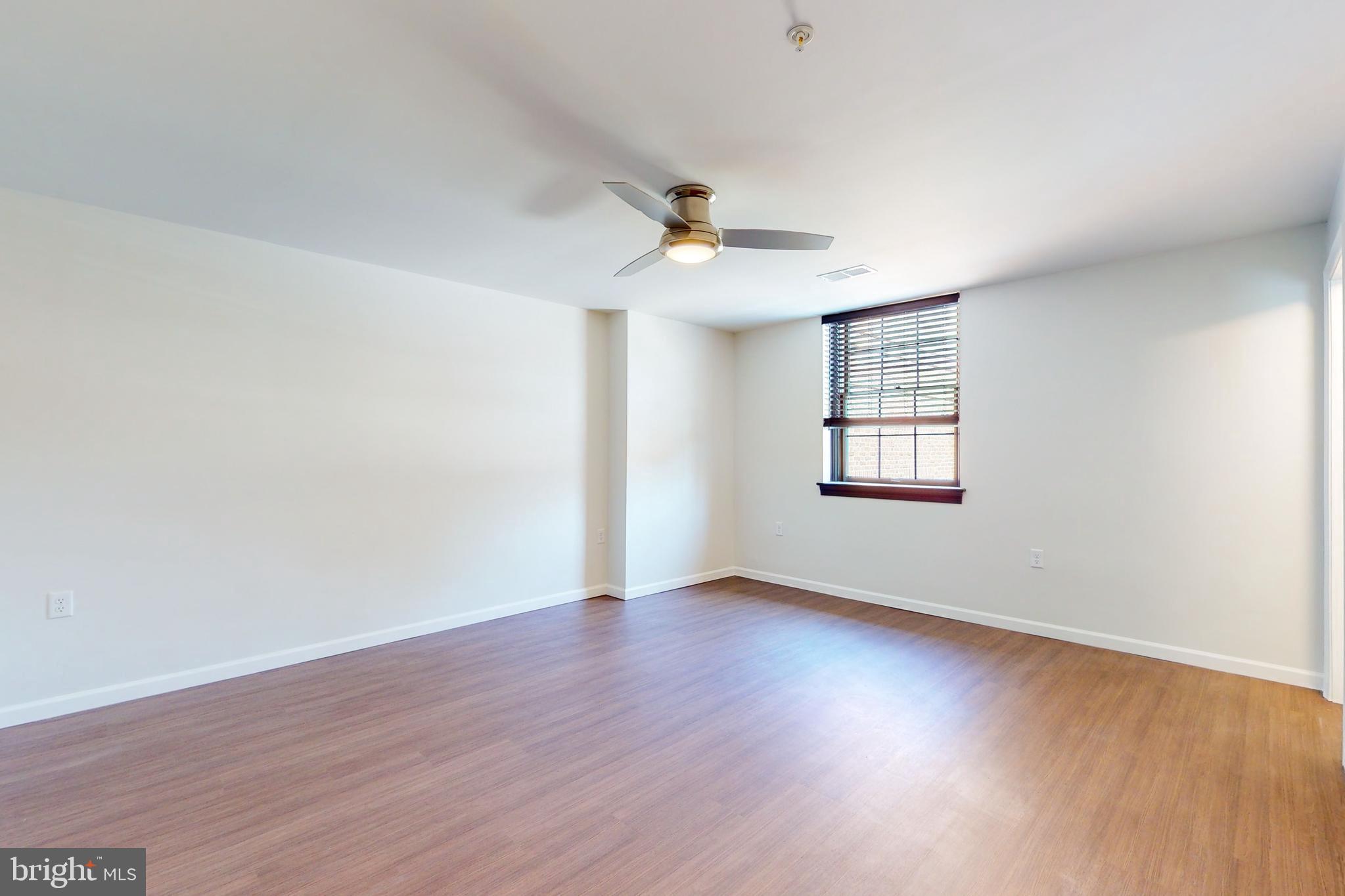 210 East Boscawen Street, Unit 204 Winchester, VA 22601 - Photo 14 of 20 an empty room with wooden floor ceiling fan and windows