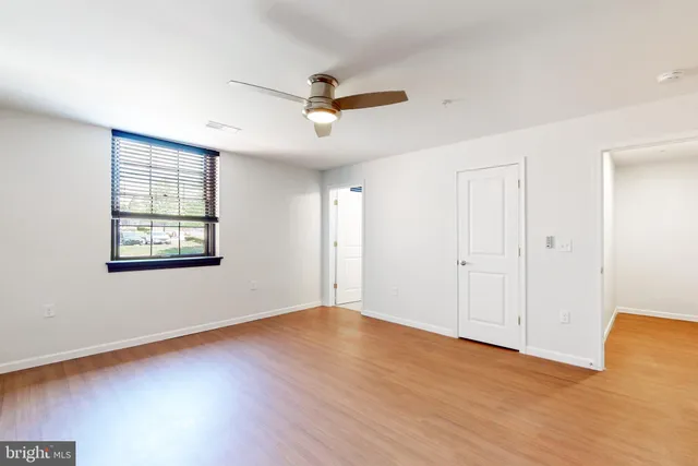 a view of an empty room with wooden floor and a window