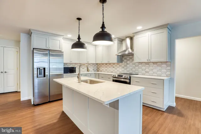 a kitchen with stainless steel appliances granite countertop a sink a stove a refrigerator and island with wooden floor