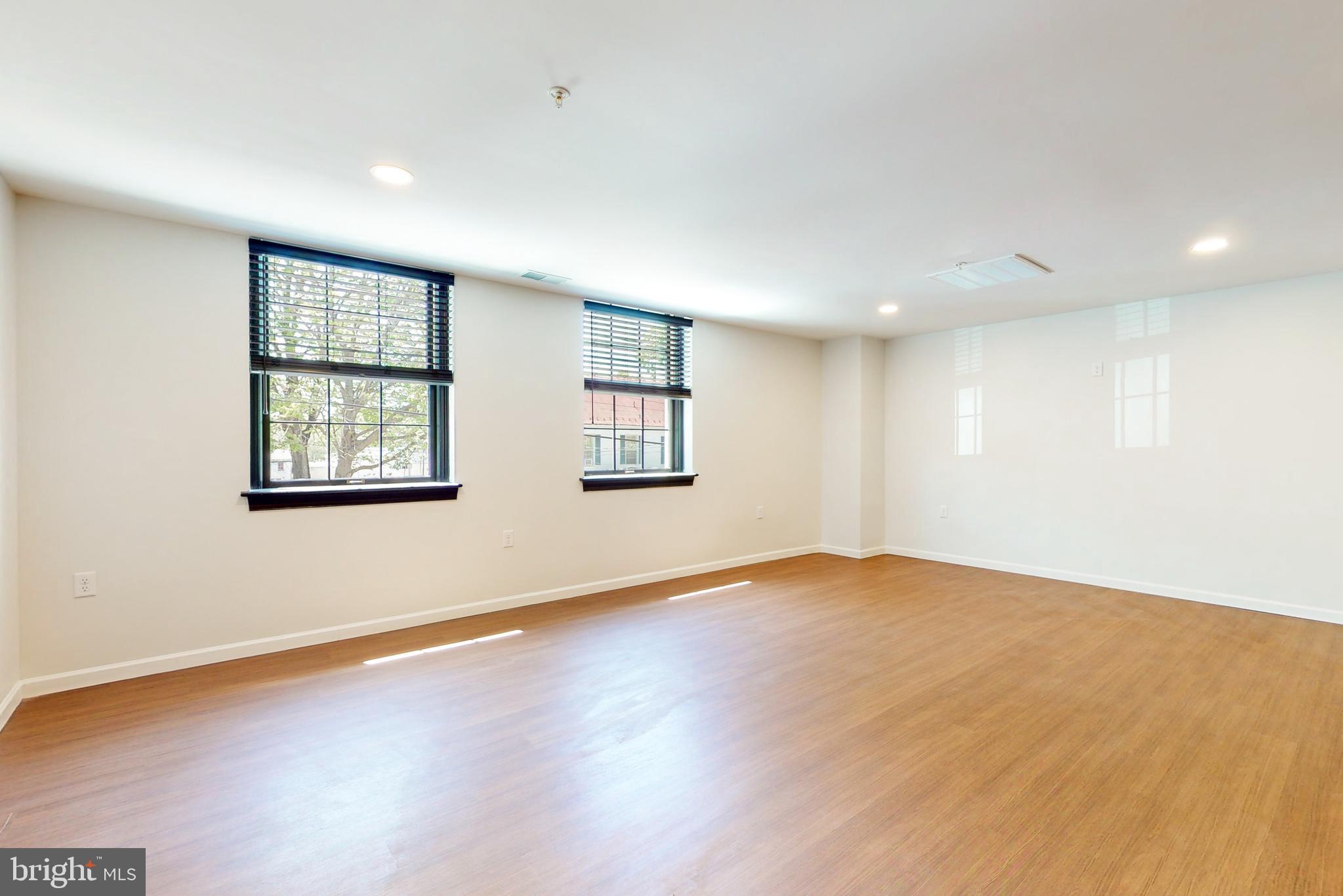 210 East Boscawen Street, Unit 204 Winchester, VA 22601 - Photo 7 of 20 an empty room with wooden floor and windows