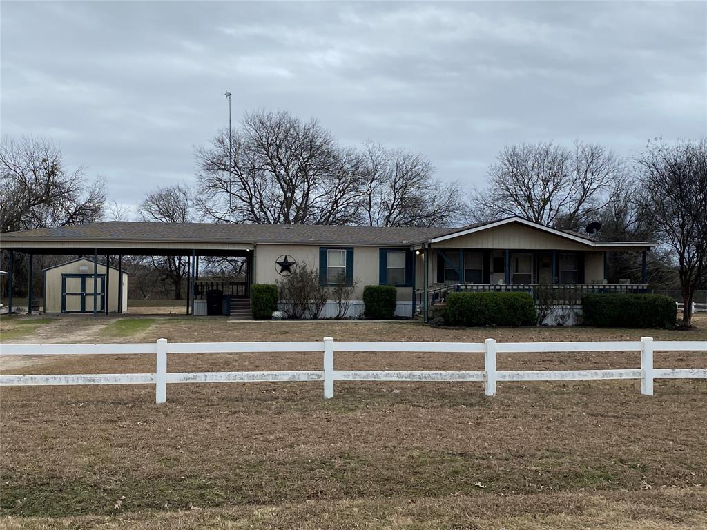 View of front facade featuring a carport, storage shed, a covered front porch