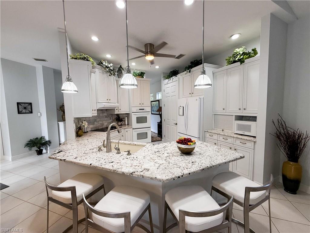 516 Eagle Creek Drive Naples, FL 34113 - Photo 12 of 28 a kitchen with a dining table cabinets stainless steel appliances and a dining table