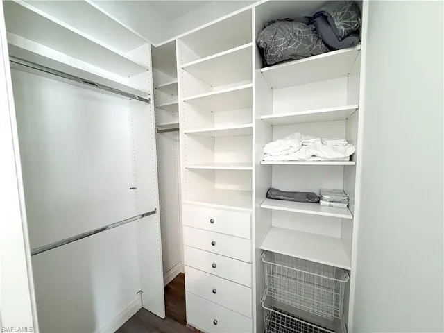 a walk in closet with white cabinets