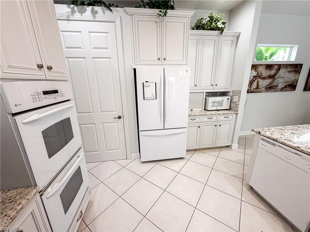 516 Eagle Creek Drive Naples, FL 34113 - Photo 10 of 28 a kitchen with white cabinets and white appliances