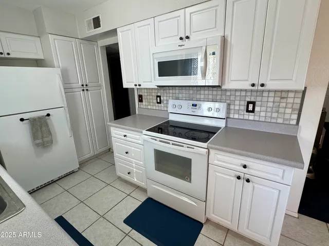 a kitchen with white cabinets and white appliances