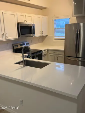 a kitchen with stainless steel appliances a refrigerator a stove a microwave a sink and cabinets