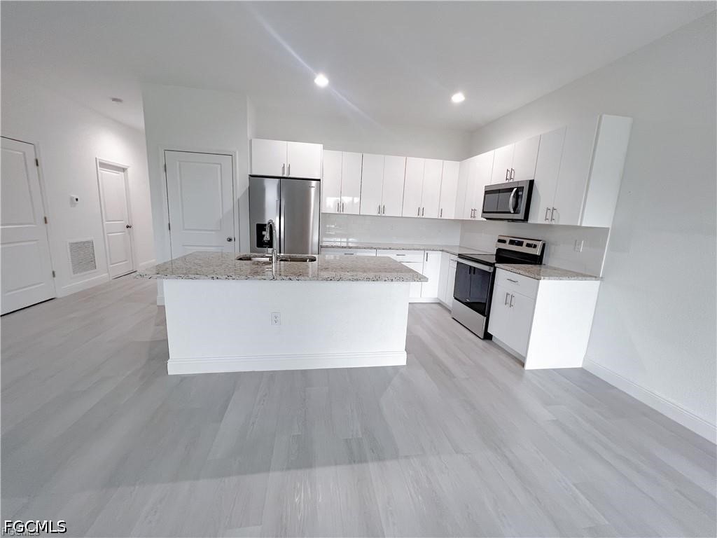 7012 Jolly Circle LaBelle, FL 33935 - Photo 3 of 12 a large kitchen with kitchen island a sink a stove a refrigerator and white cabinets